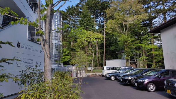 Photo of a building exterior with text "ARCHITECT GREENSEED 軽井沢 3F THE CIRCLE KARUIZAWA 1F 2F" and parked cars.