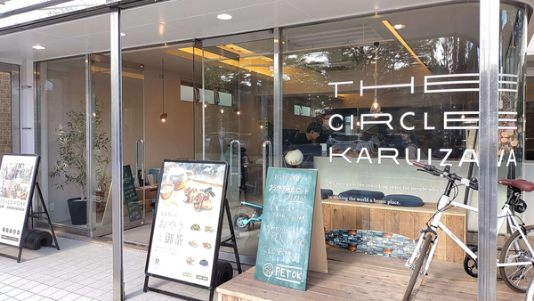 Storefront of THE CIRCLE KARUIZAWA with signage for "PETOK!" and a white bicycle parked outside.